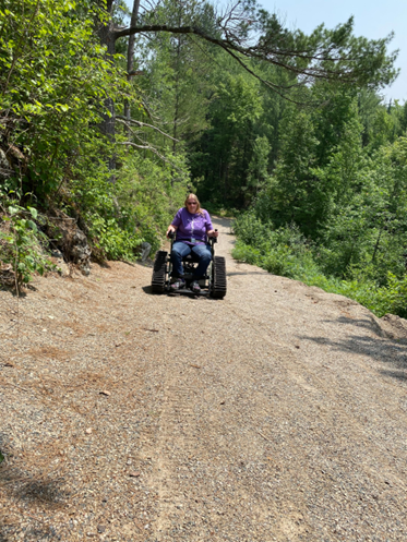 woman in outdoor wheelchair climbing steep crushed gravel trail